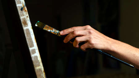 Someone painting some picture with a brush isolated on black backgroundの写真素材