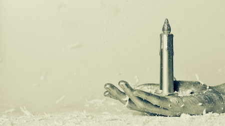 Female hand painted in silver holds a Christmas candle