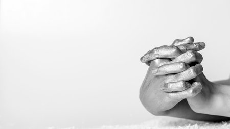 Womens hands, painted in silver, are interlocked with fingers on a gray background.の写真素材