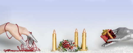 Photo Female hands, painted in silver, hold gifts against the background of a Christmas ornament.の写真素材