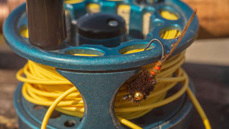 Fly fishing tackle on a wooden background, including reel and line. Close-up.