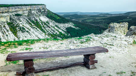 Photo A wooden bench on the top of the Crimean mountains, which offers a beautiful view.の写真素材