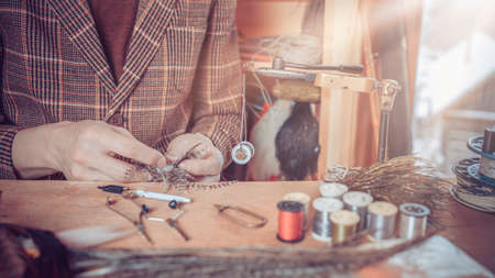 Photo Close up on young man's hands tying a fly for fishing