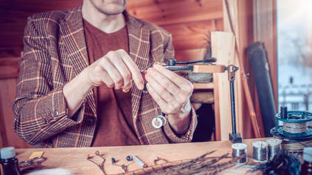 Phota Close up on young man's hands tying a fly for fishing