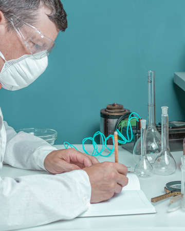 Laboratory assistant makes notes in a notebook in the laboratory. Medical, pharmaceutical and scientific research and development concept.の写真素材