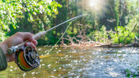 Fly fishing rod in fisherman hand. Fishing on the mountain river. Summer Activities.の写真素材