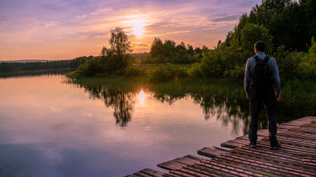 Photo Tourist looking at the lake. Sunset in the evening with rim light effect during sunset. The concept of travel and pleasant outdoor recreation.の写真素材