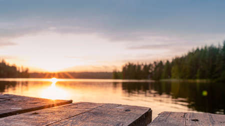 Photo Wooden pier for boats at sunset with reflection in the lake.