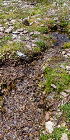 A small stream formed by melting snow in summer on the mountain. North Caucasus.