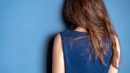 Fashionable knitted vest on the girl in the studio. The girl stands with her back.