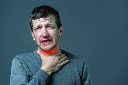 sick man has a sore throat isolated on a gray backgroundの写真素材