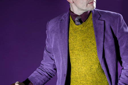 A man in a knitted vest, a classic purple jacket and a tie.の写真素材