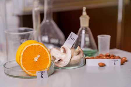 Oranges, mushrooms and nuts on a laboratory table with vitamin names. essential vitamins. food test laboratory.の写真素材