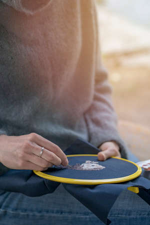 Home needlework concept, ross-stitched pillow in female hands.の写真素材