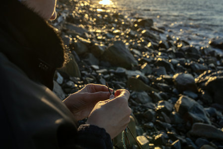 Woman knitting a blue project with the ocean in the background.の写真素材