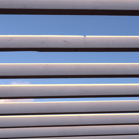 Texture of a wooden lattice roof made of parallel planks against a blue sky. Abstract urban modern background, geometric perspective.の写真素材