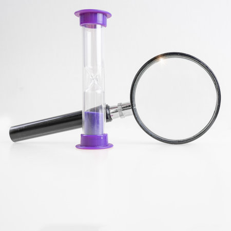 Magnifying glass and hourglass on a white background. Time to search for information on the Internet