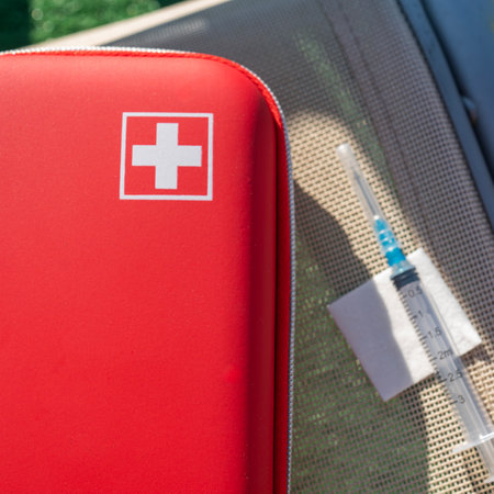 At the top is a red first aid kit with a white cross, next to it is a syringe and an alcohol wipe....