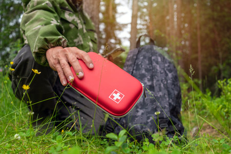 A man holding a red first aid kit, camping in the forest. Tourism conceptの写真素材