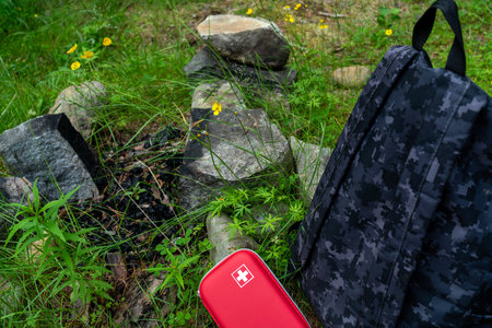 Red first aid kit next to a backpack, camping in the forest. Tourism conceptの写真素材