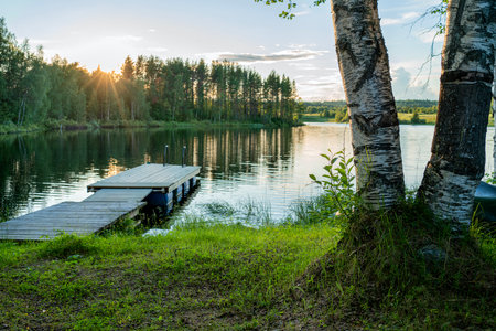 Beautiful sunset with sun rays in lush summer taiga and beautiful lake in national parkの写真素材