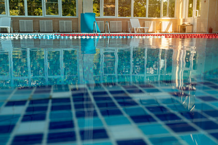 An indoor swimming pool awaits swimmers for training or leisure. the clear blue water and lane markers indicate a facility designed for both competitive and recreational swimming.の写真素材