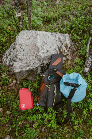 Red first aid kit next to a backpack, camping in the forest. Tourism concept.の写真素材
