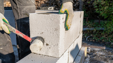 Bricklayer putting down another row of bricks in siteの写真素材