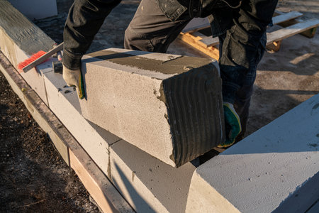 bricklayer builder working with autoclaved aerated concrete blocks. Walling, installing bricks on...