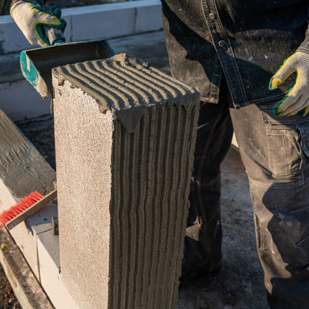bricklayer builder working with autoclaved aerated concrete blocks. Walling, installing bricks on construction site, Engineering and constructions concepts.の写真素材