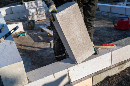 bricklayer builder working with autoclaved aerated concrete blocks. Walling, installing bricks on construction site, Engineering and constructions concepts.の写真素材