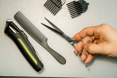 Hairdresser's hands holding hair cutting tools on white background.の写真素材