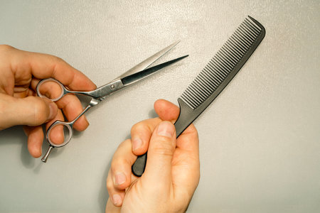Hairdresser's hands holding hair cutting tools on white background.の写真素材