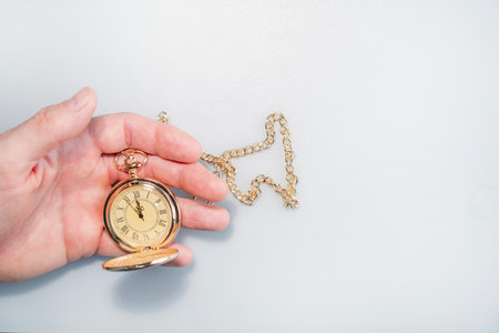 Hand with a watch on a white background, the clock shows five minutes to twelve. Mysticism, fortune telling, New Year.の写真素材