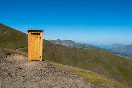 A wooden house on a mountainside. In the background are the majestic peaks of a mountain range in a national park.の写真素材