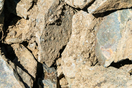A close-up of the texture of rough, broken rock. The image captures the natural process of decay and...