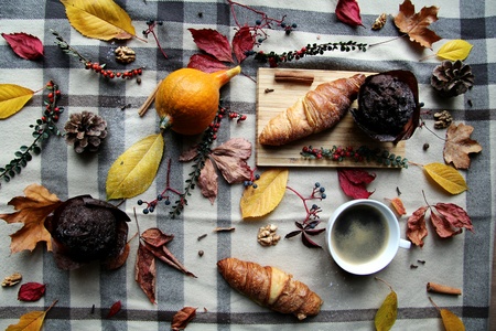 Colorful Autum themed background with Chocolate Muffin, Croissant, Pumpkin, Leavesの写真素材