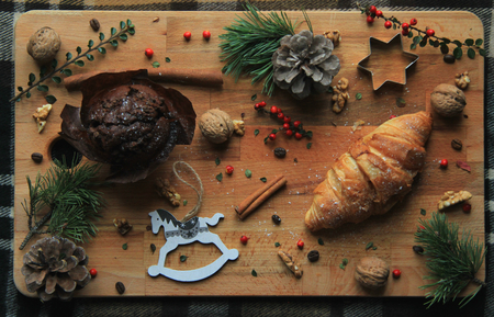 Christmas Themed Background With Chocolate Muffin, Croissant, Pine Cone, Hazelnuts, Cinnamonの写真素材