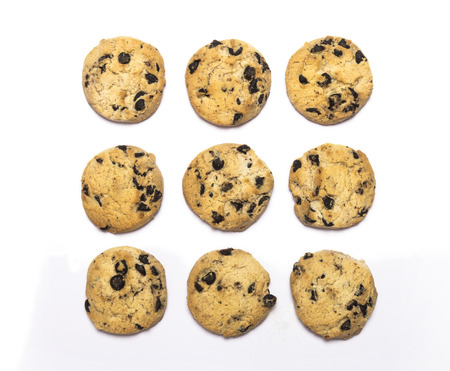 Crispy sweet chocolate chip cookies arranged on white background photographed from a high angle in...