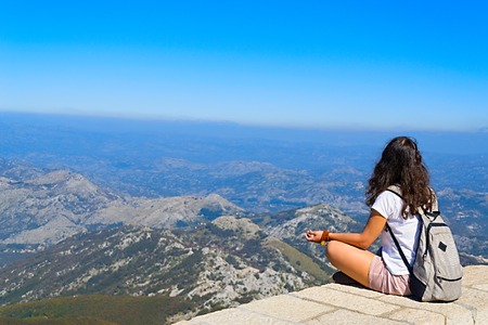 girl sitting on the Mount Lovcen in Montenegro among the clouds and look at the panorama of the mountainsの写真素材