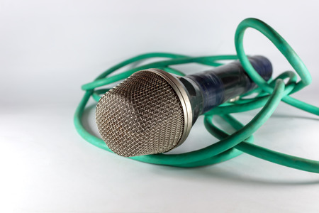 Old microphone with green cable on light backgroundの写真素材