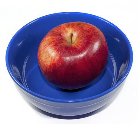 Red apple in a blue bowl on a white backgroundの写真素材