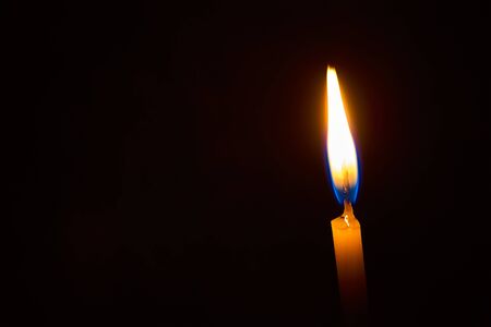 One Burning candle on a black background