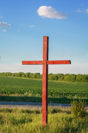 Roadside painted wooden cross on a background of fieldの写真素材