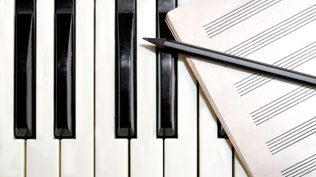 Keyboard with music sheet and pencil close upの写真素材