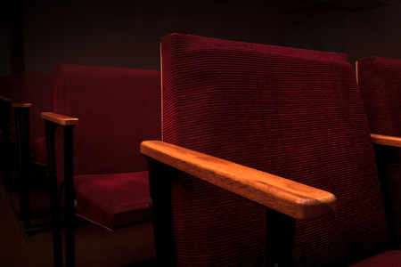 Rows of red armchairs of the dark auditorium of the cinemaの写真素材
