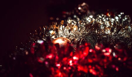 Blurred dark festive background with a warm shade from tinsel with a ballの写真素材