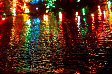 Multi-colored lights on a dark background on a reflective surfaceの写真素材