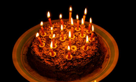 Birthday cake with candles on a platter on a dark backgroundの写真素材