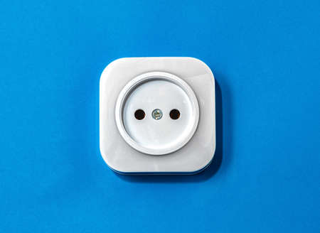 Electric white plastic socket on a blue backgroundの写真素材